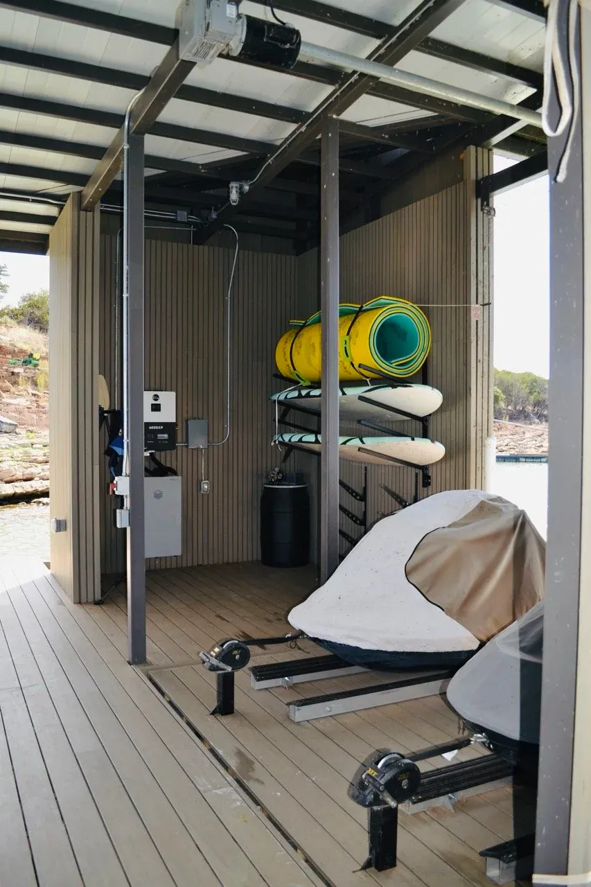 Boathouse storage room with paddleboards, a kayak rack and a covered PWC
