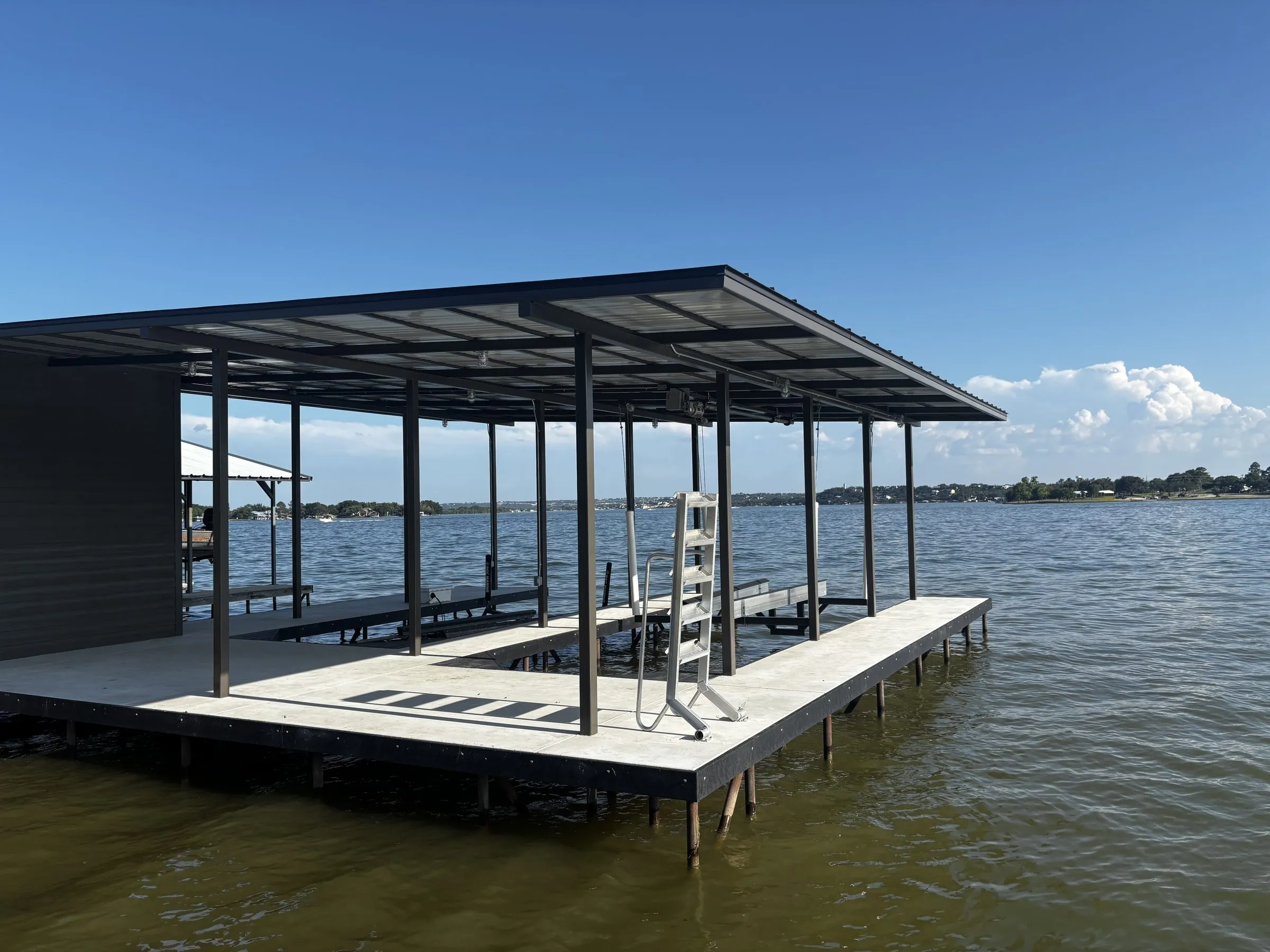 Modern stationary boathouse with a flat steel roof, enclosed storage room and concrete deck on open lake water