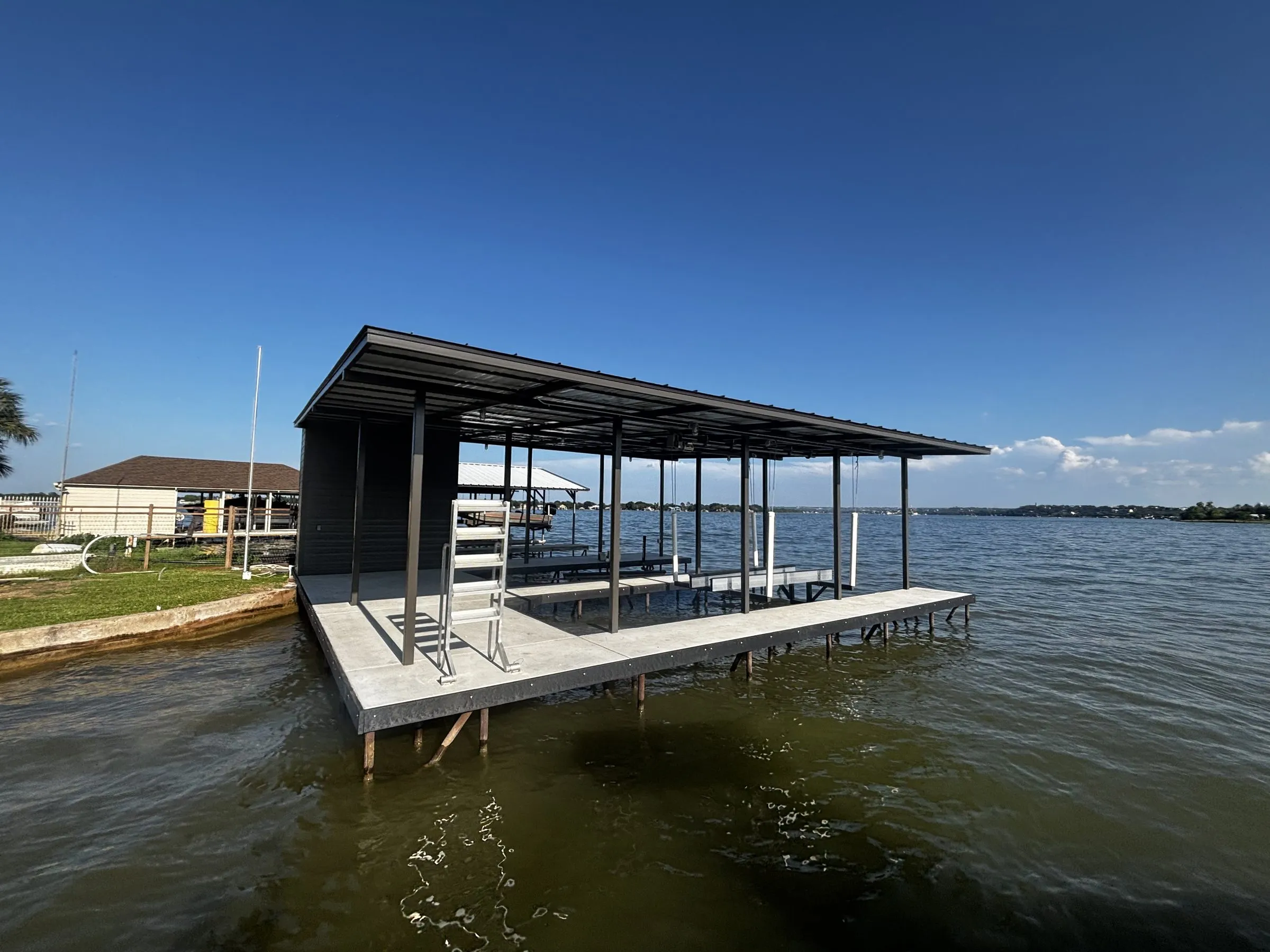 Corner of the boathouse showing the storage room wall, concrete walkway and slender steel columns