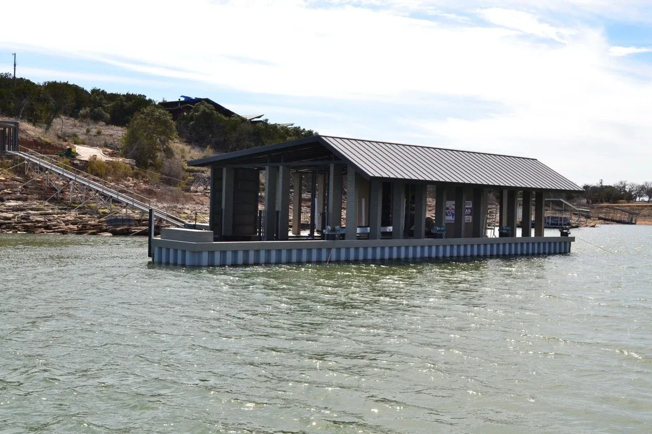 Side view of the floating boathouse below a rocky Hill Country shoreline