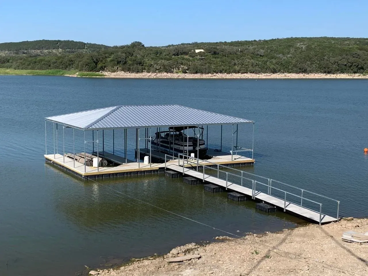 Covered floating dock with a long aluminum gangway on a wide lake