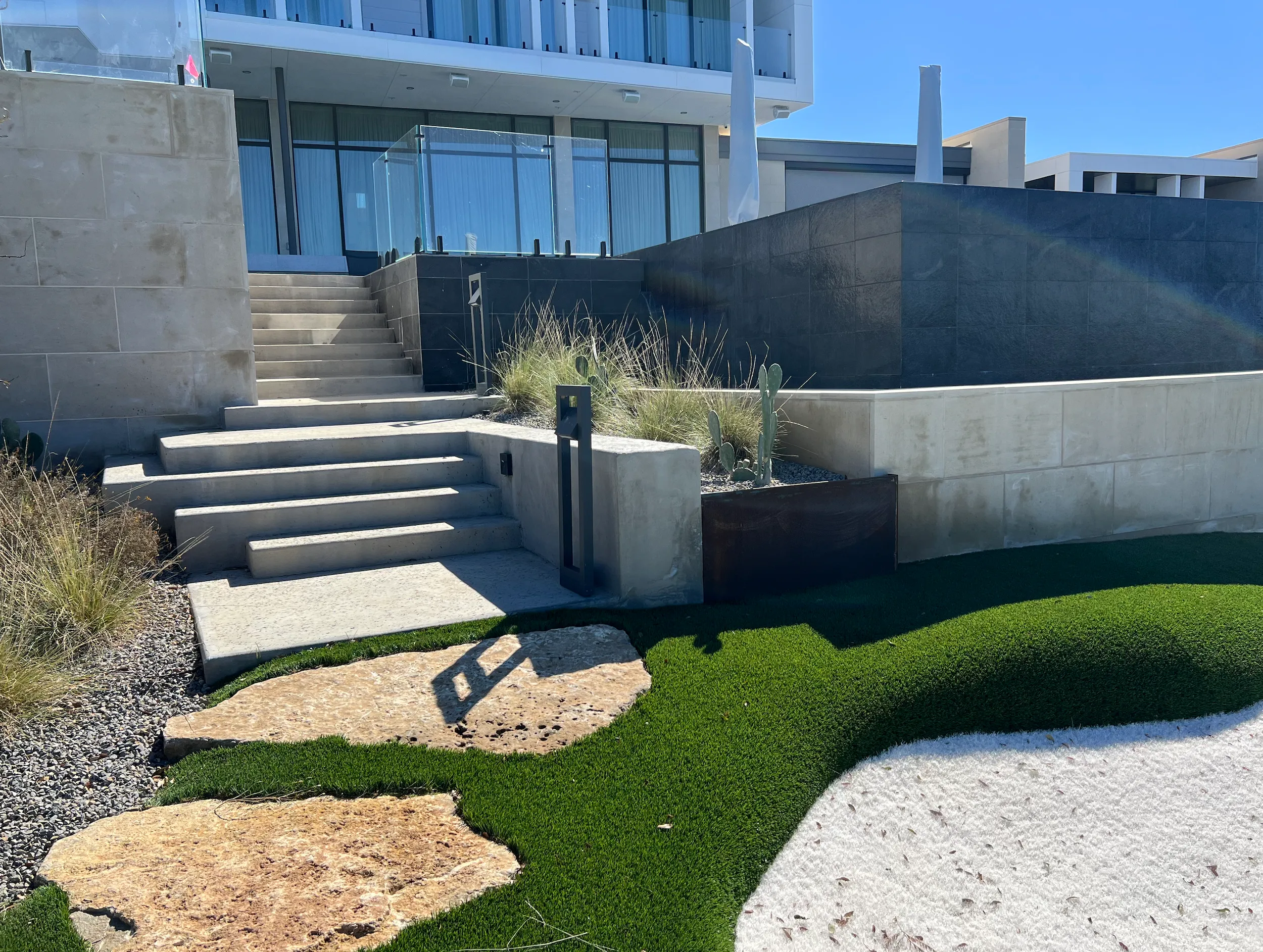 Limestone steps and steel edging leading up to a modern lake house